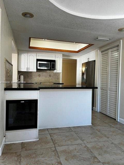 1325 N 74th Terrace, #0, Hollywood, Hollywood, FL 33024 Kitchen featuring white cabinetry, dark countertops, built-in stainless steel oven, recessed tray ceiling, and ceramic tile flooring
