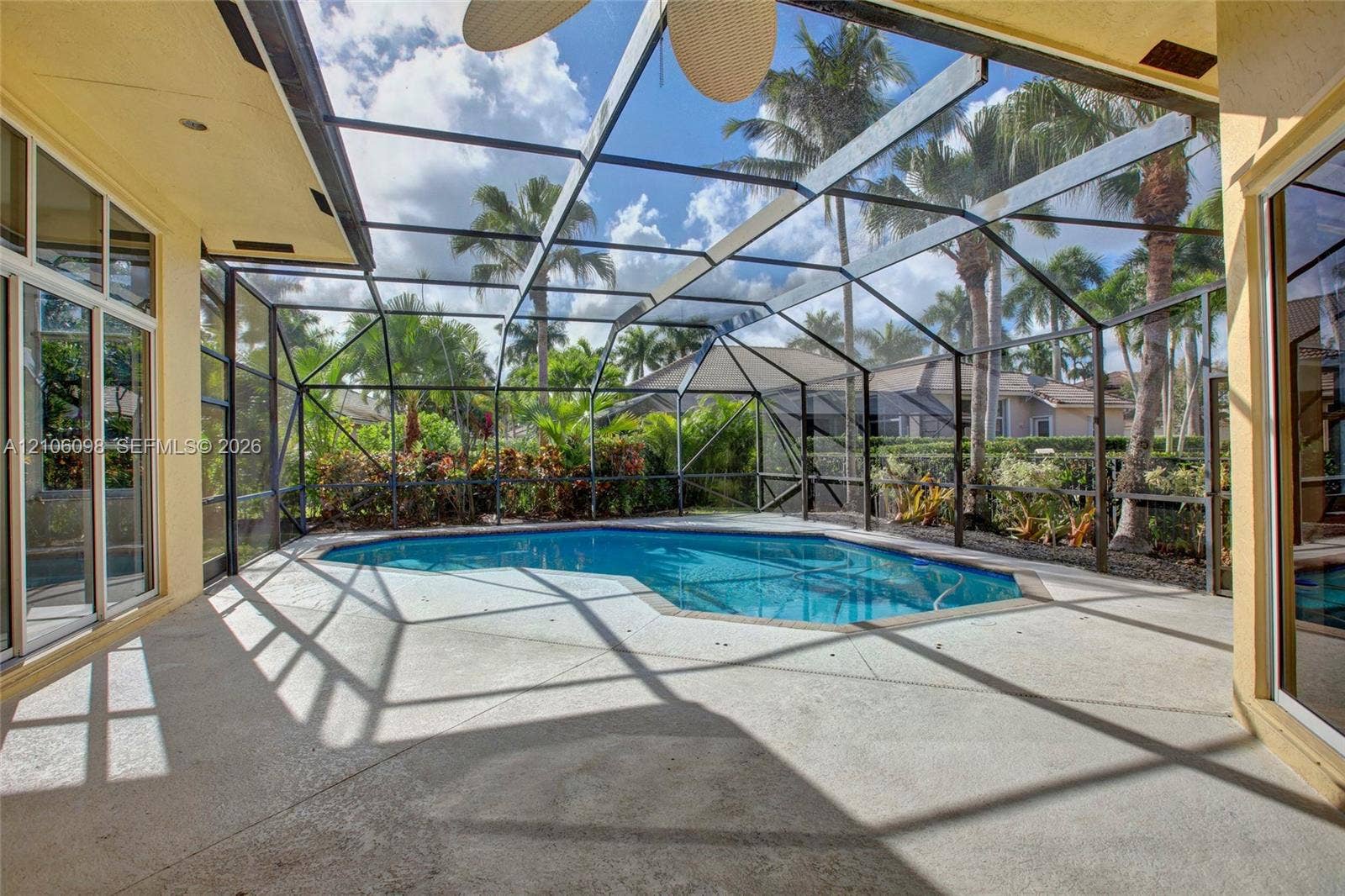 Screened-in patio featuring a concrete deck, swimming pool, and ceiling fan