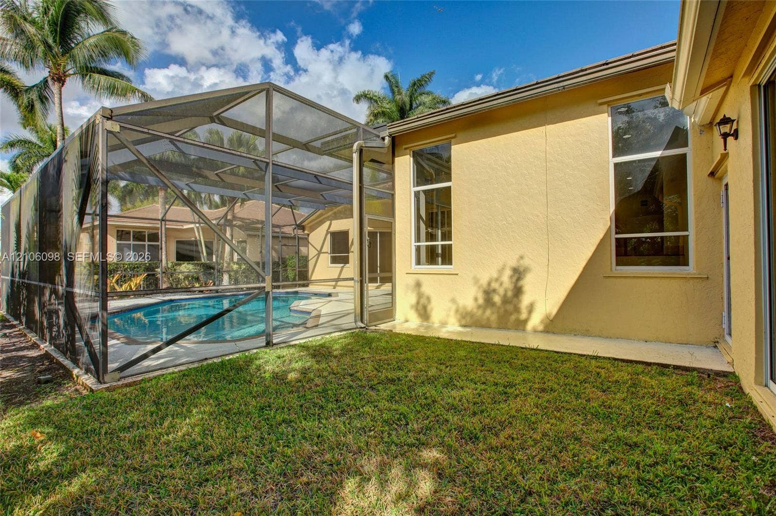 Screened-in pool enclosure featuring a concrete patio deck, stucco exterior walls, and tall vertical windows