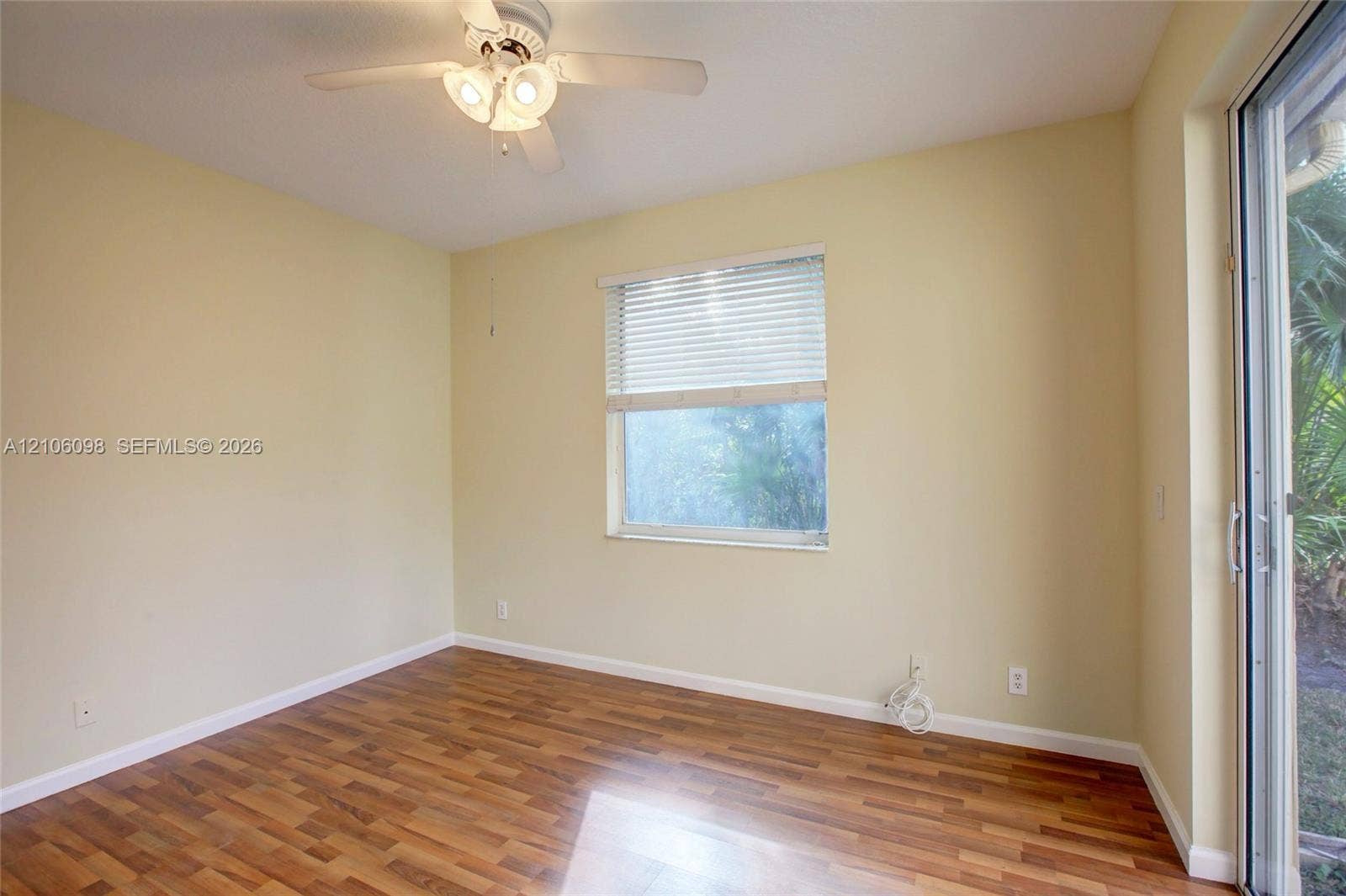 Wood-finish flooring, ceiling fan with integrated lighting, horizontal window blinds, and sliding glass door