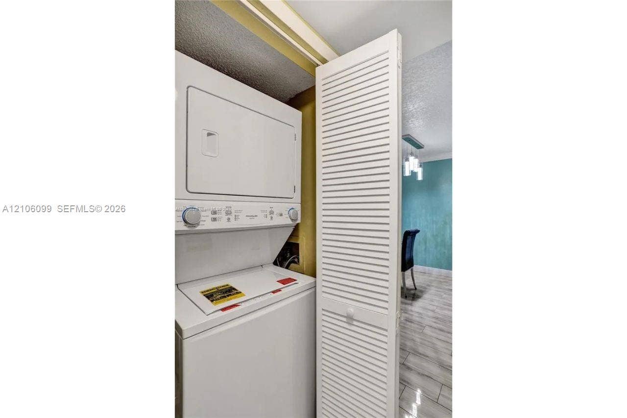 7840 NW 50th Street, #105, Lauderhill, FL 33351 Stackable white laundry unit housed within a closet featuring a white louvered door