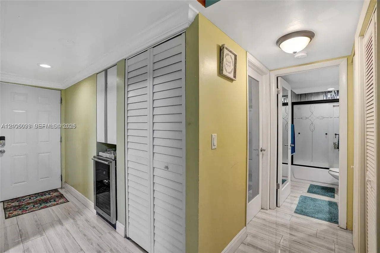 7840 NW 50th Street, #105, Lauderhill, FL 33351 Interior hallway featuring wood-finish flooring, built-in beverage refrigerator with cabinetry, louvered closet doors, and recessed ceiling lighting