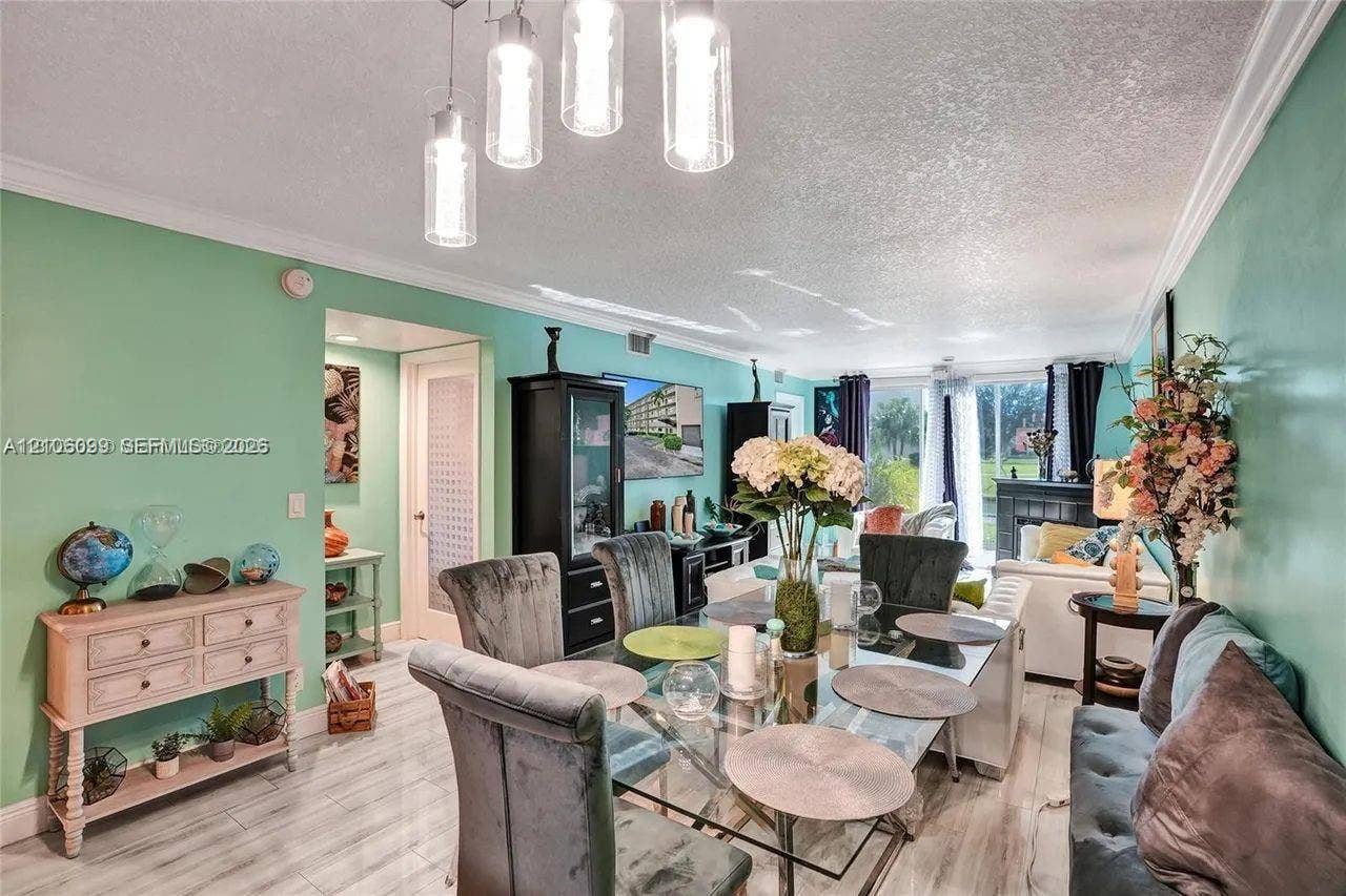 7840 NW 50th Street, #105, Lauderhill, FL 33351 Living area featuring wood-finish tile flooring, crown molding, multi-pendant glass lighting, and sliding glass doors
