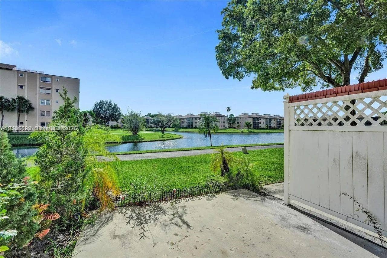 7840 NW 50th Street, #105, Lauderhill, FL 33351 Concrete patio featuring a lattice-topped privacy screen, overlooking a water feature and landscaped grounds