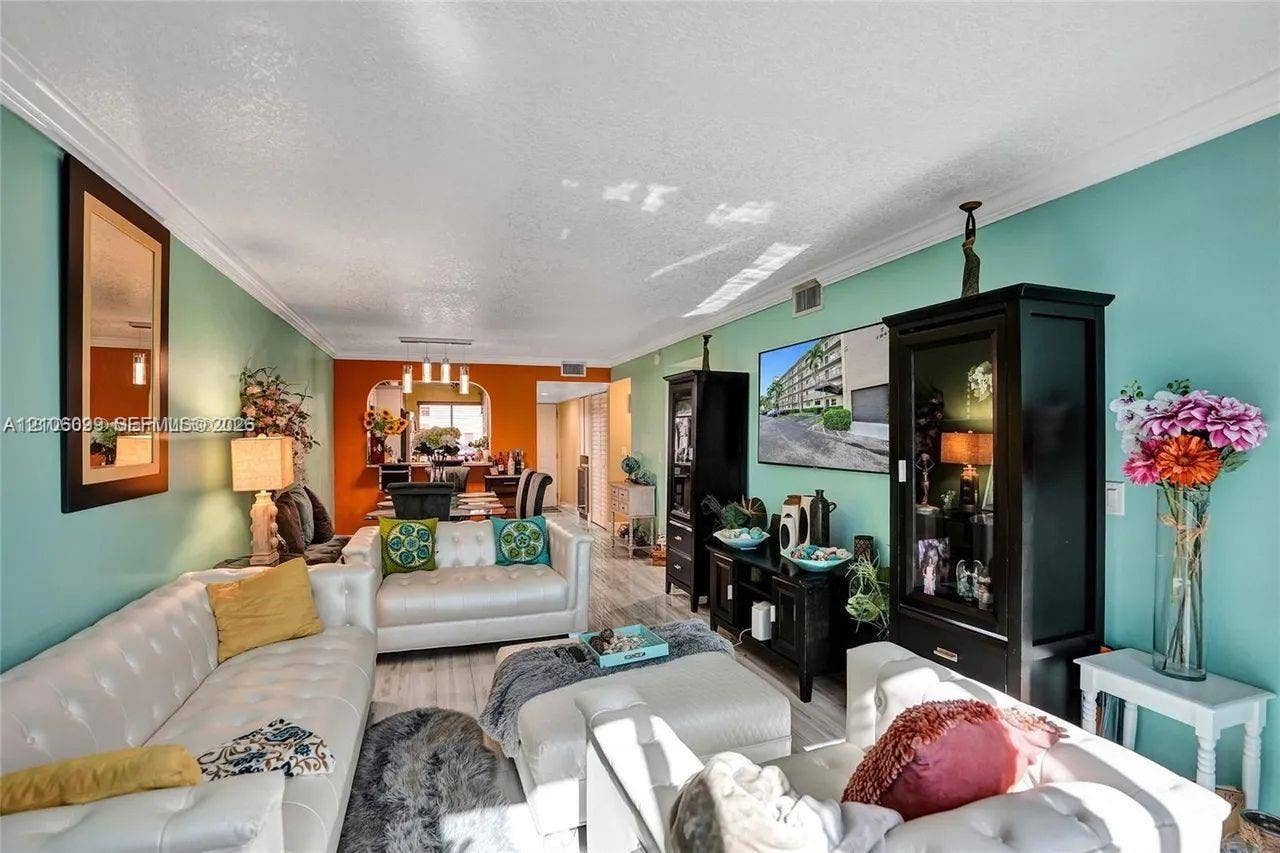 7840 NW 50th Street, #105, Lauderhill, FL 33351 Living area featuring wood-finish flooring, crown molding, and an arched entryway