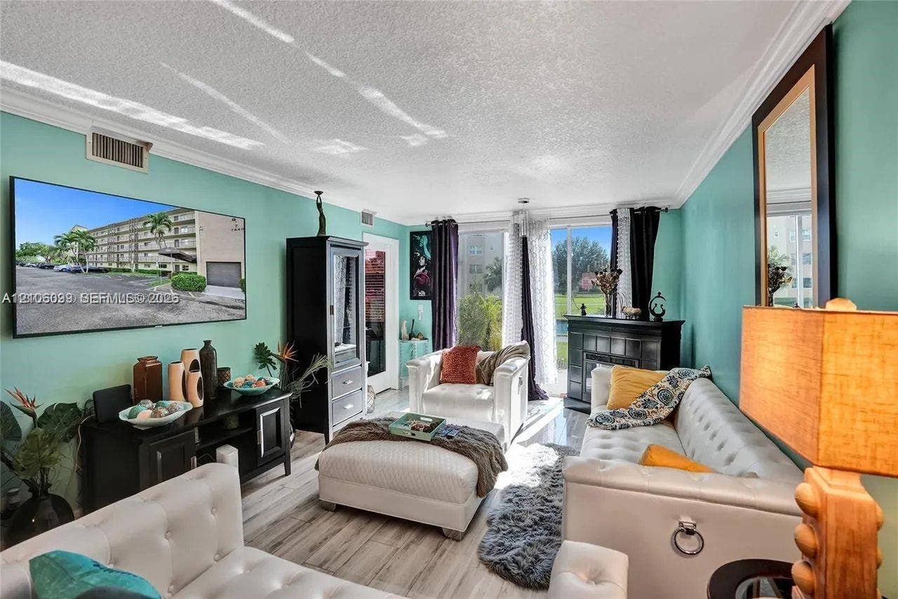 7840 NW 50th Street, #105, Lauderhill, FL 33351 Living area featuring wood-finish flooring, crown molding, and floor-to-ceiling glass sliding doors