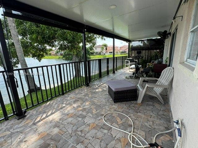 16284 SW 100th Terrace, Miami, FL 33196 Covered patio featuring stone-tile flooring, metal perimeter railing, recessed ceiling lighting, and waterfront positioning