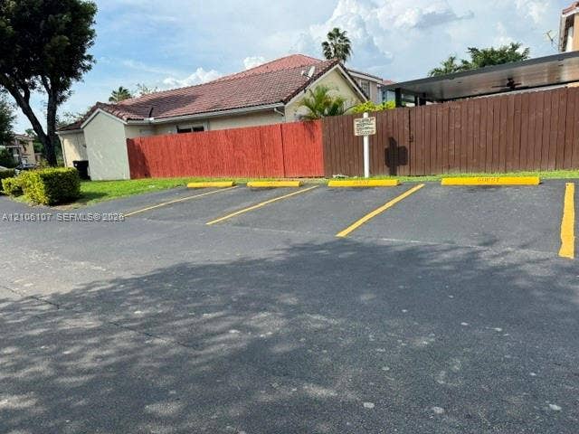 16284 SW 100th Terrace, Miami, FL 33196 Asphalt surface parking area with four designated stalls, painted yellow wheel stops, and a tall wood perimeter fence