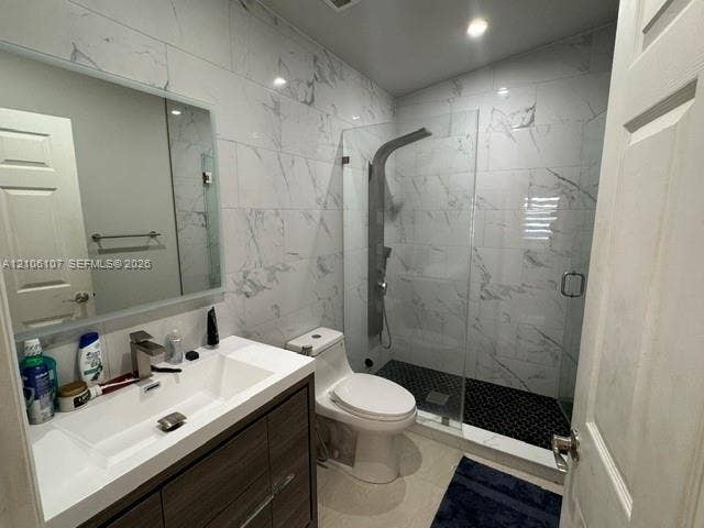 16284 SW 100th Terrace, Miami, FL 33196 Bathroom featuring a wood-finish vanity with an integrated basin, frameless glass walk-in shower with a rainfall shower panel, wall-to-wall large-format tile, and a backlit mirror
