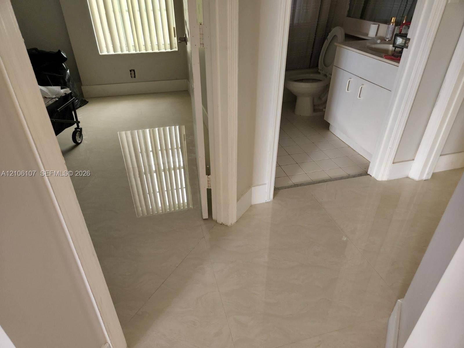 16284 SW 100th Terrace, Miami, FL 33196 Polished large-format tile flooring, vanity with integrated basin, and window featuring vertical blinds