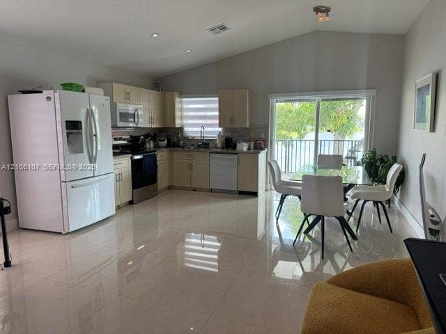 16284 SW 100th Terrace, Miami, FL 33196 Kitchen featuring vaulted ceilings, gloss-finish tile flooring, light-toned cabinetry, stainless steel appliances, and sliding glass doors