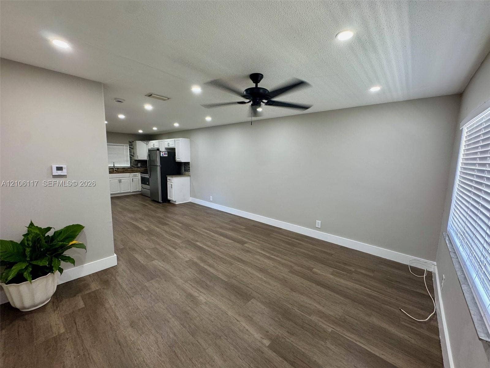 Open-concept interior featuring wood-finish flooring, recessed lighting, a matte black ceiling fan, and white cabinetry