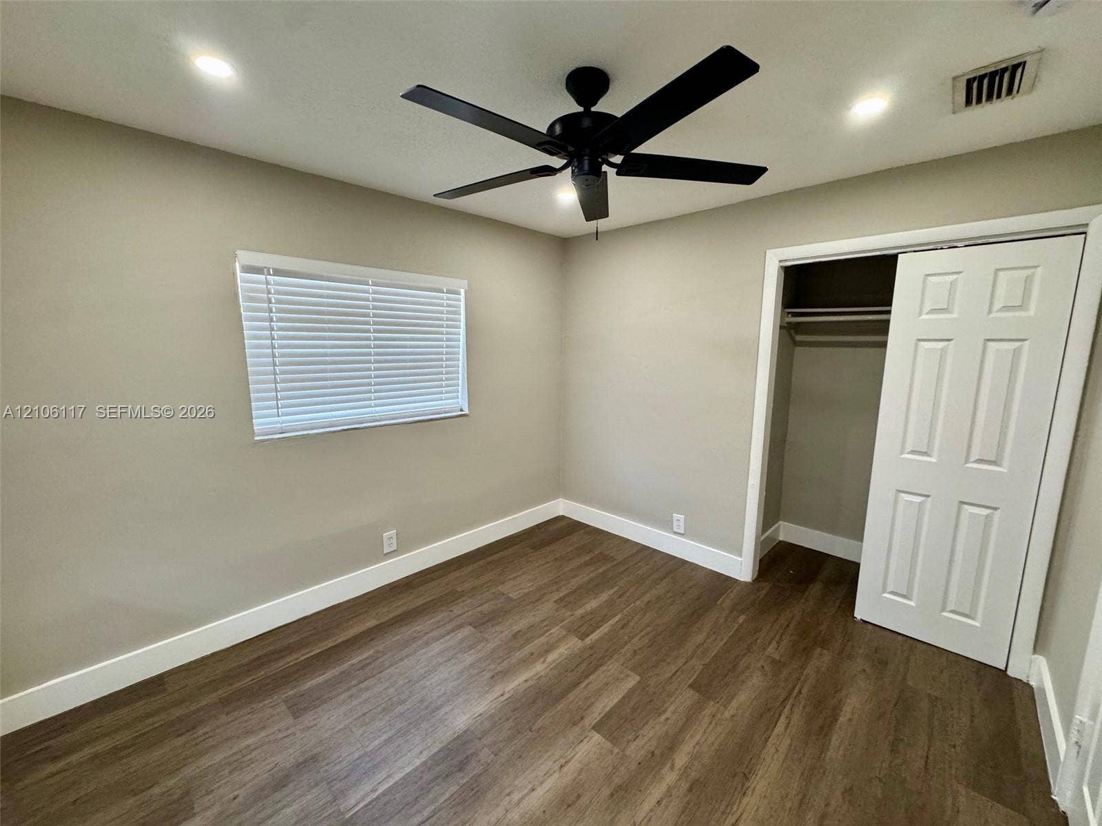 Wood-finish flooring, recessed ceiling lighting, matte black ceiling fan, and reach-in closet with panel door