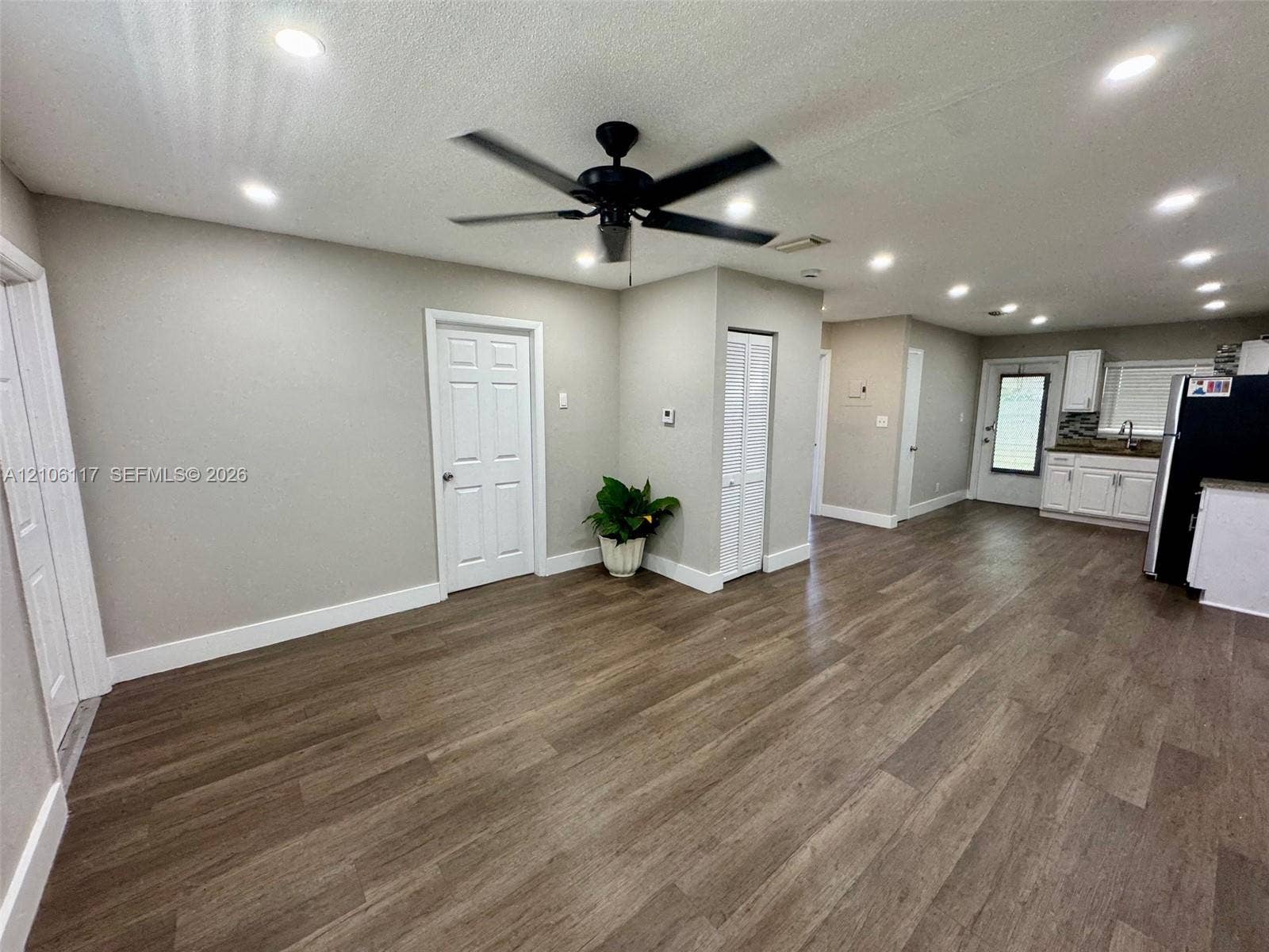 Open-concept interior featuring wood-finish flooring, recessed lighting, a ceiling fan, and white shaker-style cabinetry with neutral countertops
