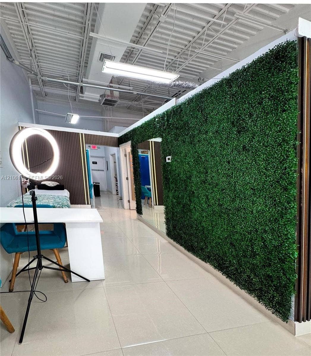 Industrial-style interior featuring a decorative faux-foliage accent wall, large-format tile flooring, exposed ceiling rafters, and vertical wood-slat wall paneling