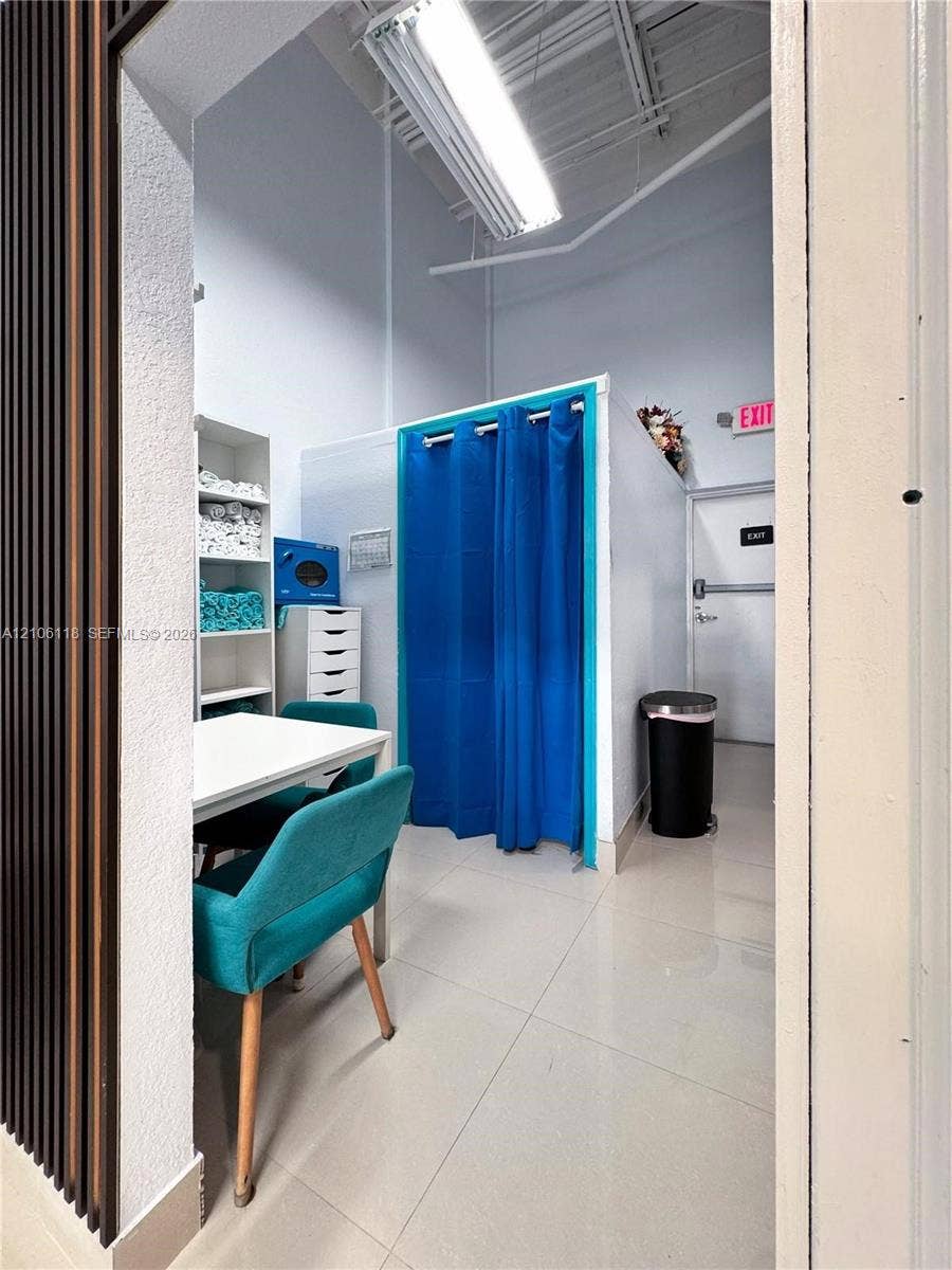 High-ceiling workspace featuring polished tile flooring, vertical slat wall paneling, built-in shelving, and exposed industrial-style lighting