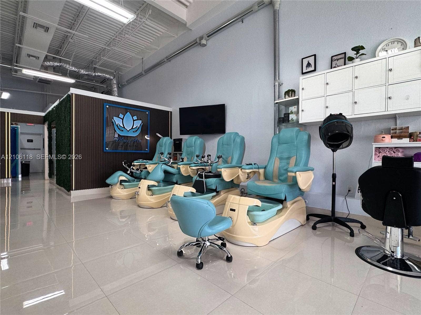 Expansive commercial space featuring high exposed ceilings, polished tile flooring, built-in white wall cabinetry, and vertical slat wall paneling
