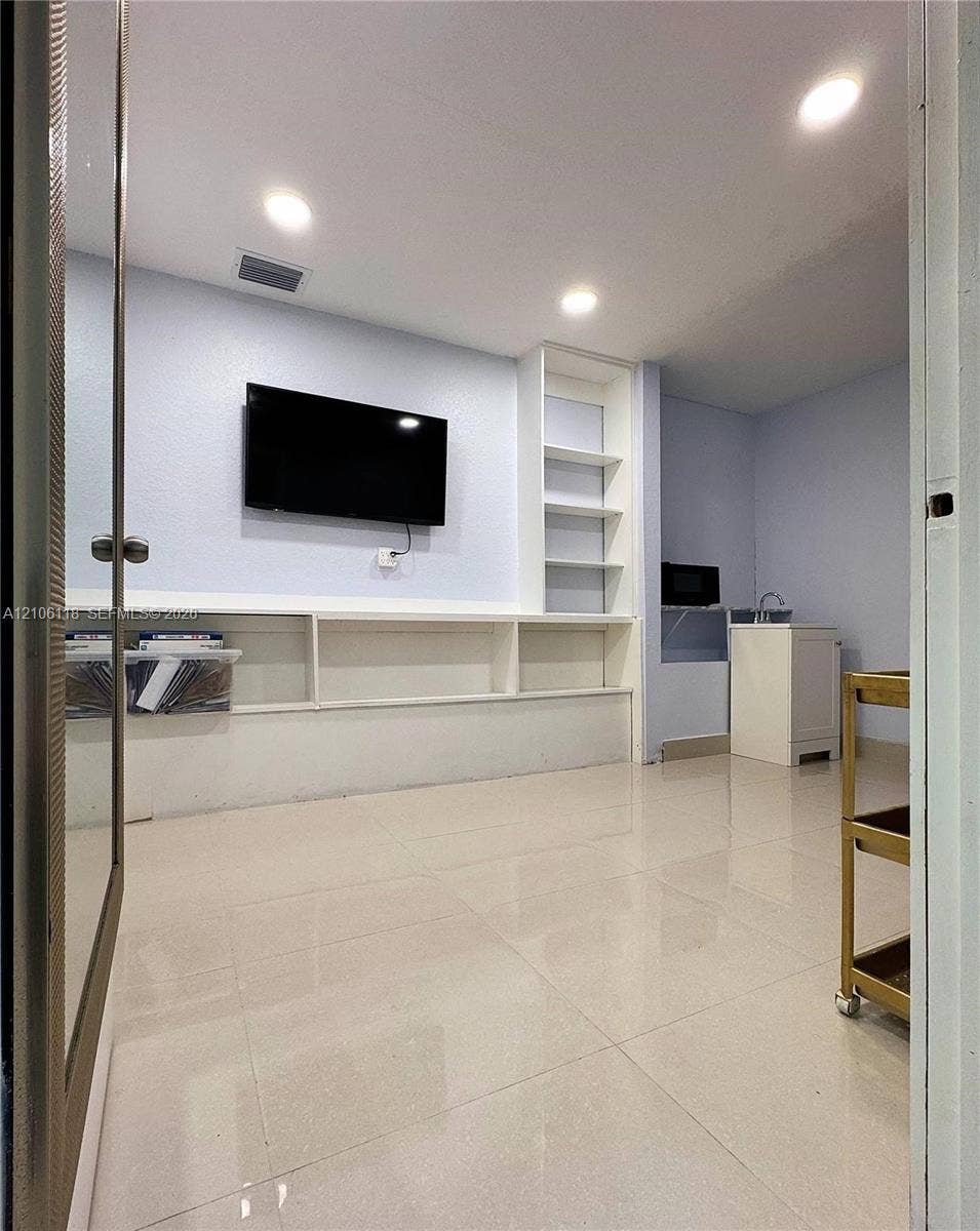 Polished tile flooring, built-in shelving, recessed lighting, and a kitchenette cabinet with a sink