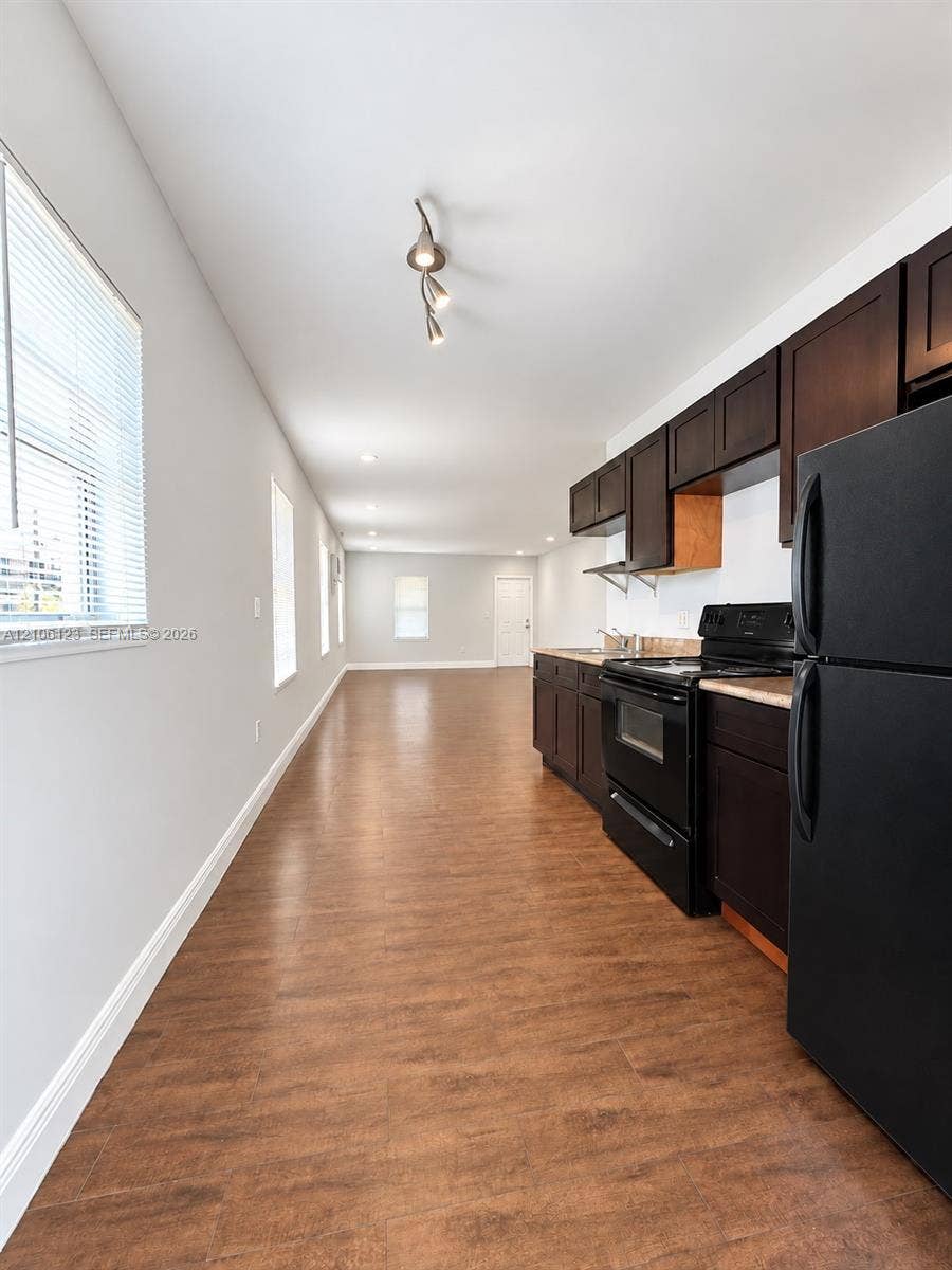123 NW 15th Street, #U, Miami, Miami, FL 33136 Kitchen featuring dark cabinetry, black built-in appliances, wood-finish flooring, recessed ceiling lighting, and multiple windows