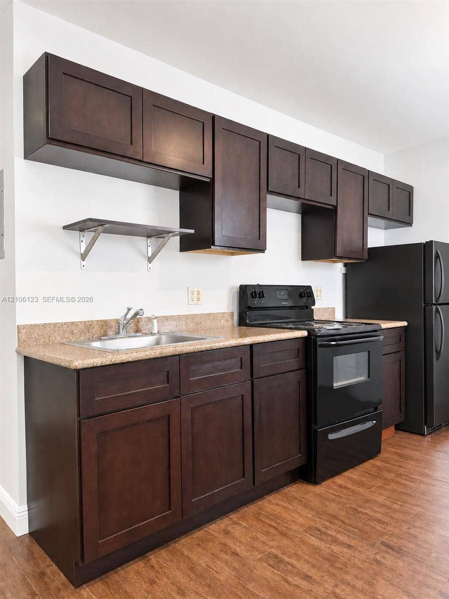 123 NW 15th Street, #U, Miami, Miami, FL 33136 Dark wood cabinetry, stone-finish countertops, stainless steel sink, wall-mounted shelving, and wood-finish flooring