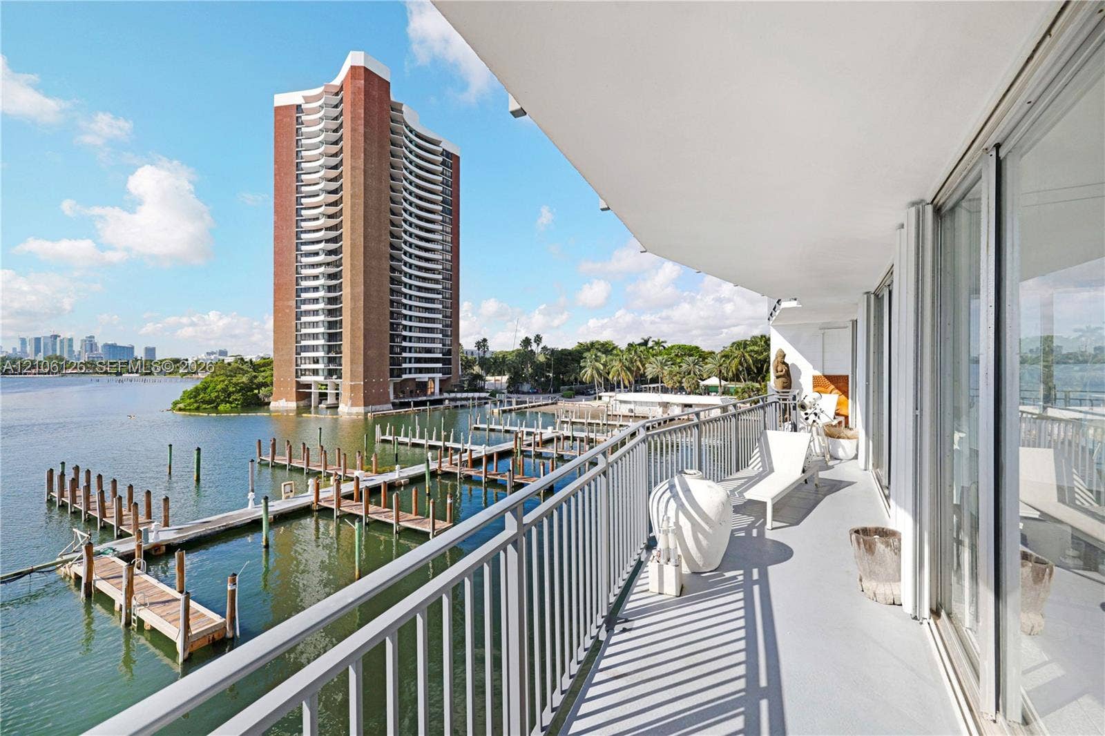 Covered balcony featuring metal railings, smooth surface flooring, and floor-to-ceiling glass sliding doors