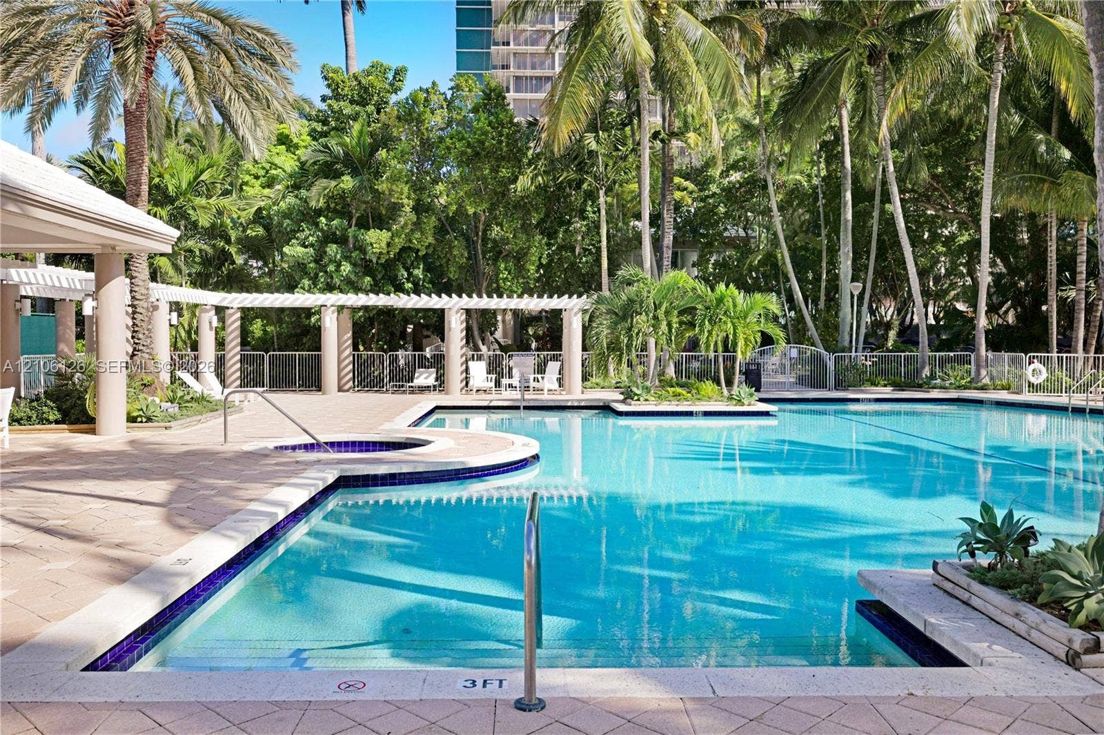 Swimming pool with tile surround, integrated spa, pergola-covered terrace, and landscaped perimeter