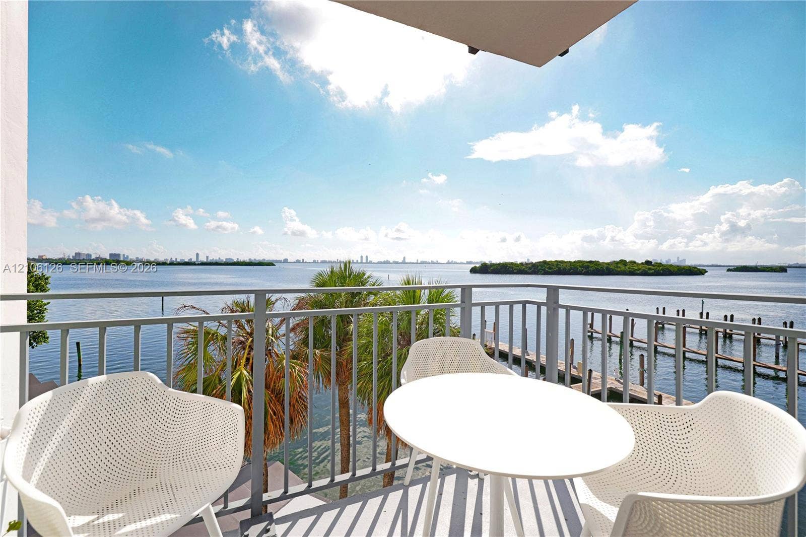 Covered balcony featuring metal railings, overhead lighting, and water-facing orientation overlooking a pier and coastal islands
