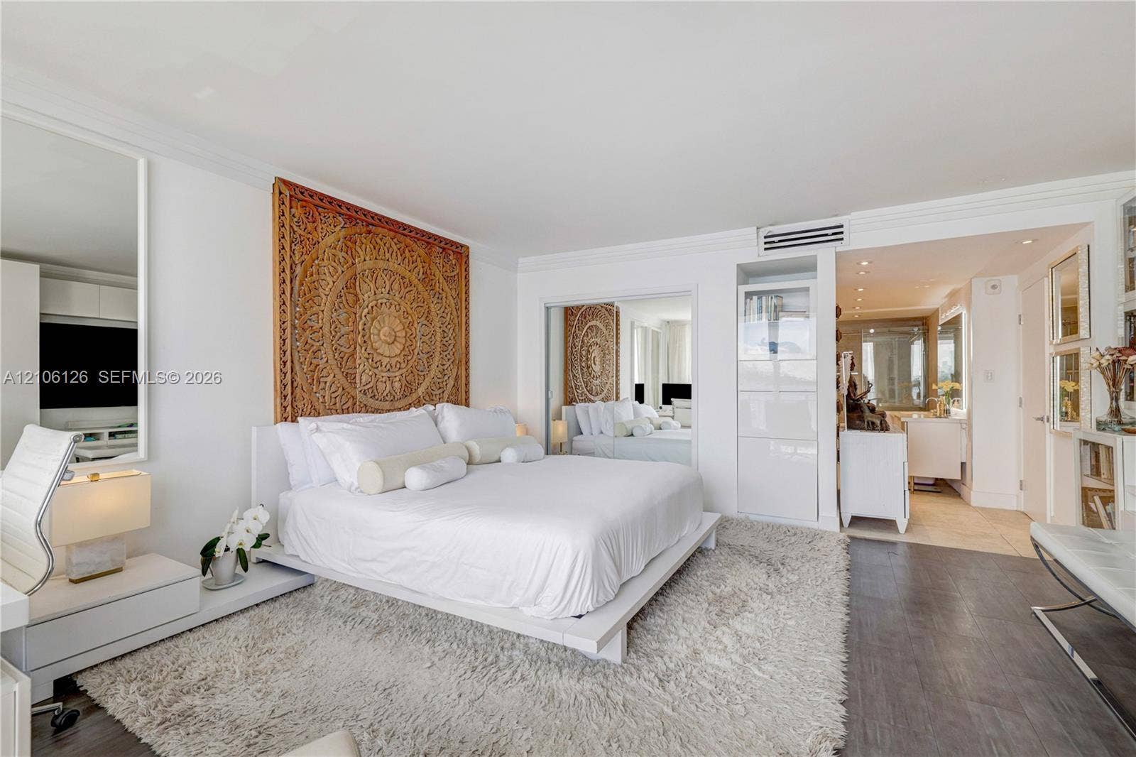 Living space featuring crown molding, wall-mounted air conditioning unit, wood-finish flooring, and mirrored closet doors