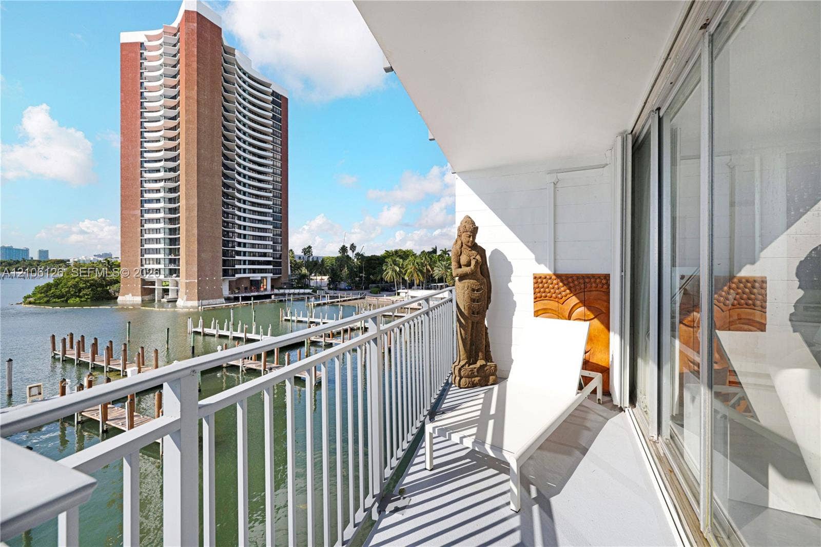 Covered balcony featuring white metal railings, smooth concrete flooring, and full-height sliding glass doors