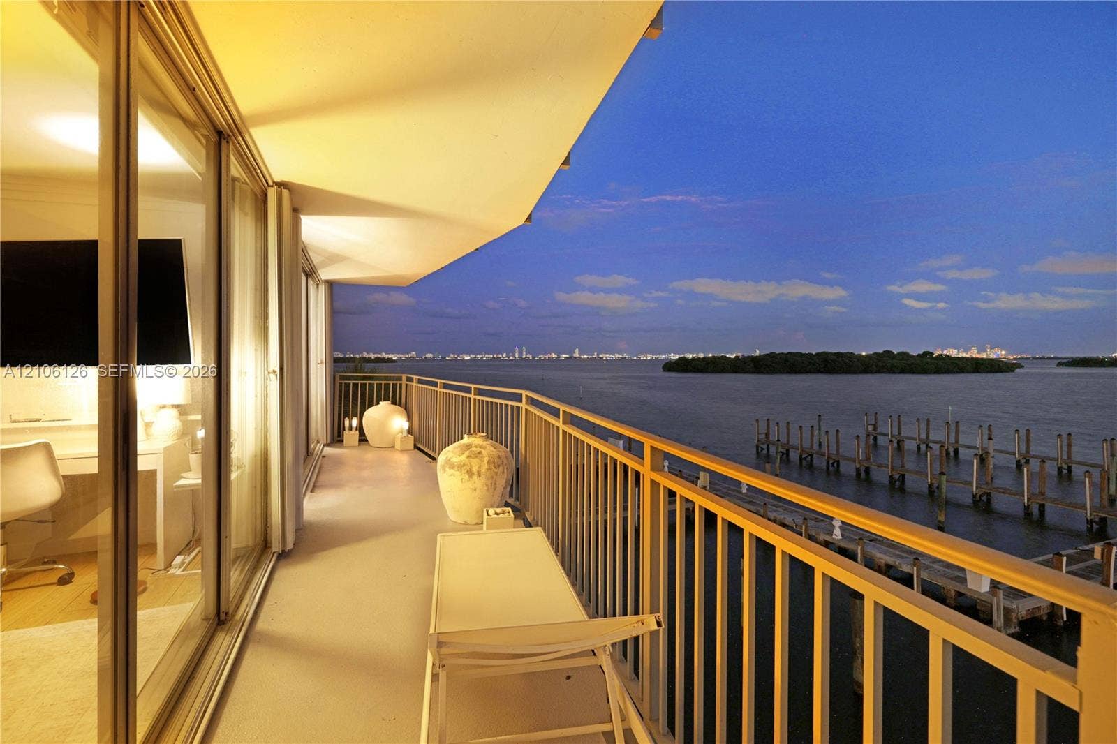 Covered balcony with a metal railing, floor-to-ceiling glass sliding doors, and water scenery