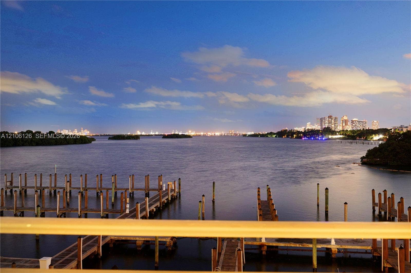 Waterfront property featuring multiple wooden boat docks and deep-water access with a distant city skyline backdrop