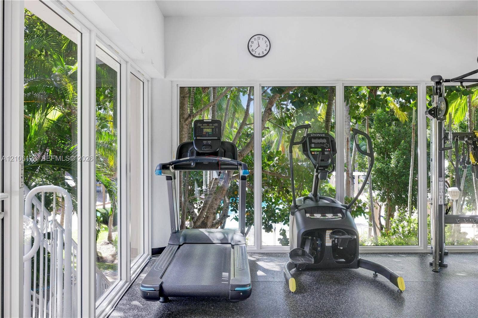 Floor-to-ceiling glass wall panels with expansive exterior foliage and rubberized flooring