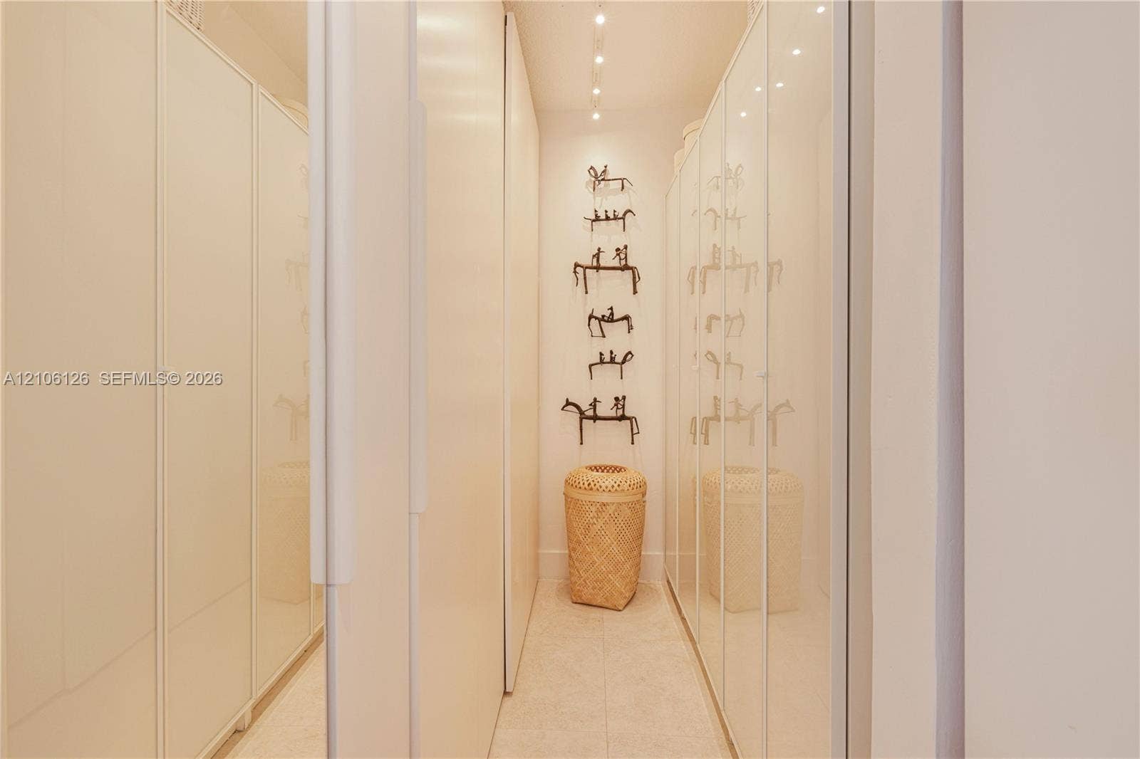 Full-height cabinetry with high-gloss white finish, recessed ceiling track lighting, and neutral stone-finish flooring
