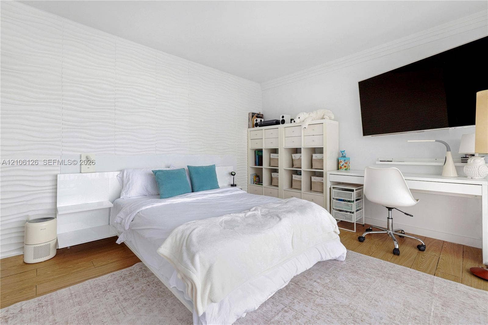 Textured feature wall, wood-finish flooring, and built-in headboard cabinetry