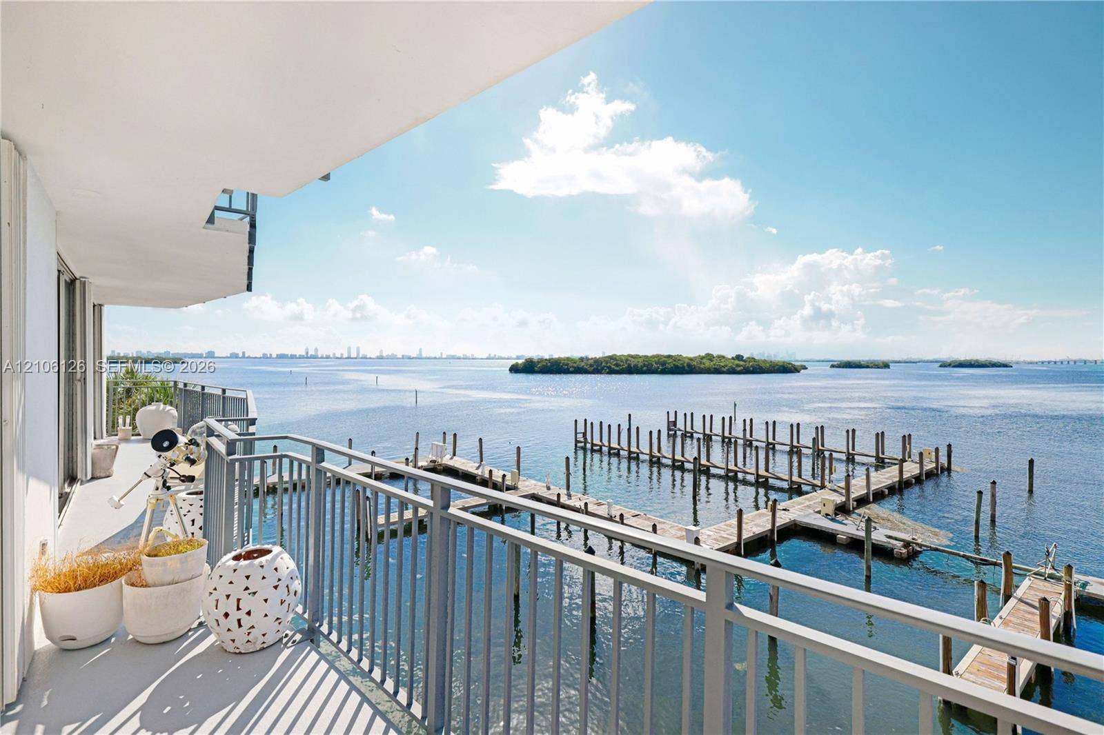 Covered balcony featuring a metal railing and expansive water frontage with a private dock system