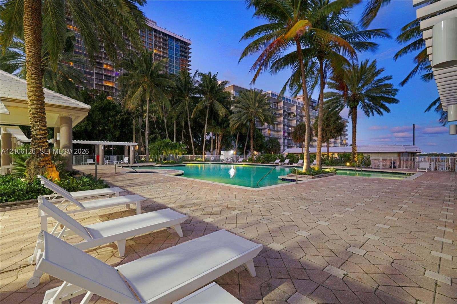 Outdoor swimming pool with brick paver decking, integrated spa, and mature palm trees