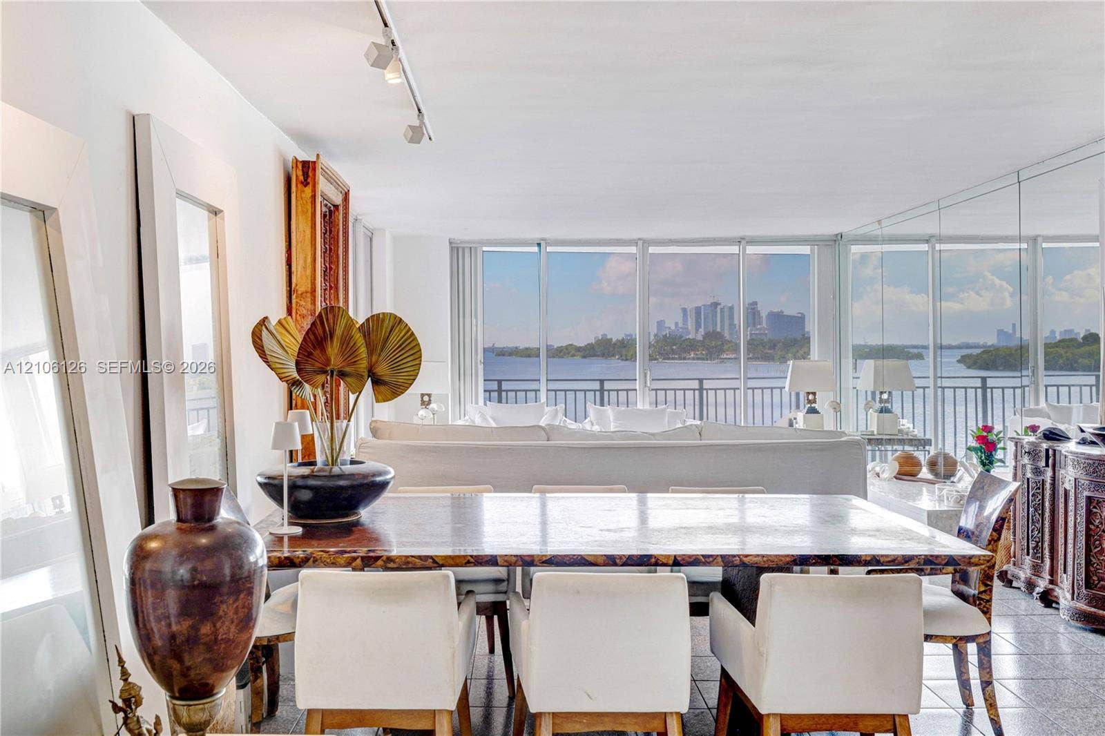 Floor-to-ceiling windows, mirrored wall accents, track lighting, and tiled flooring