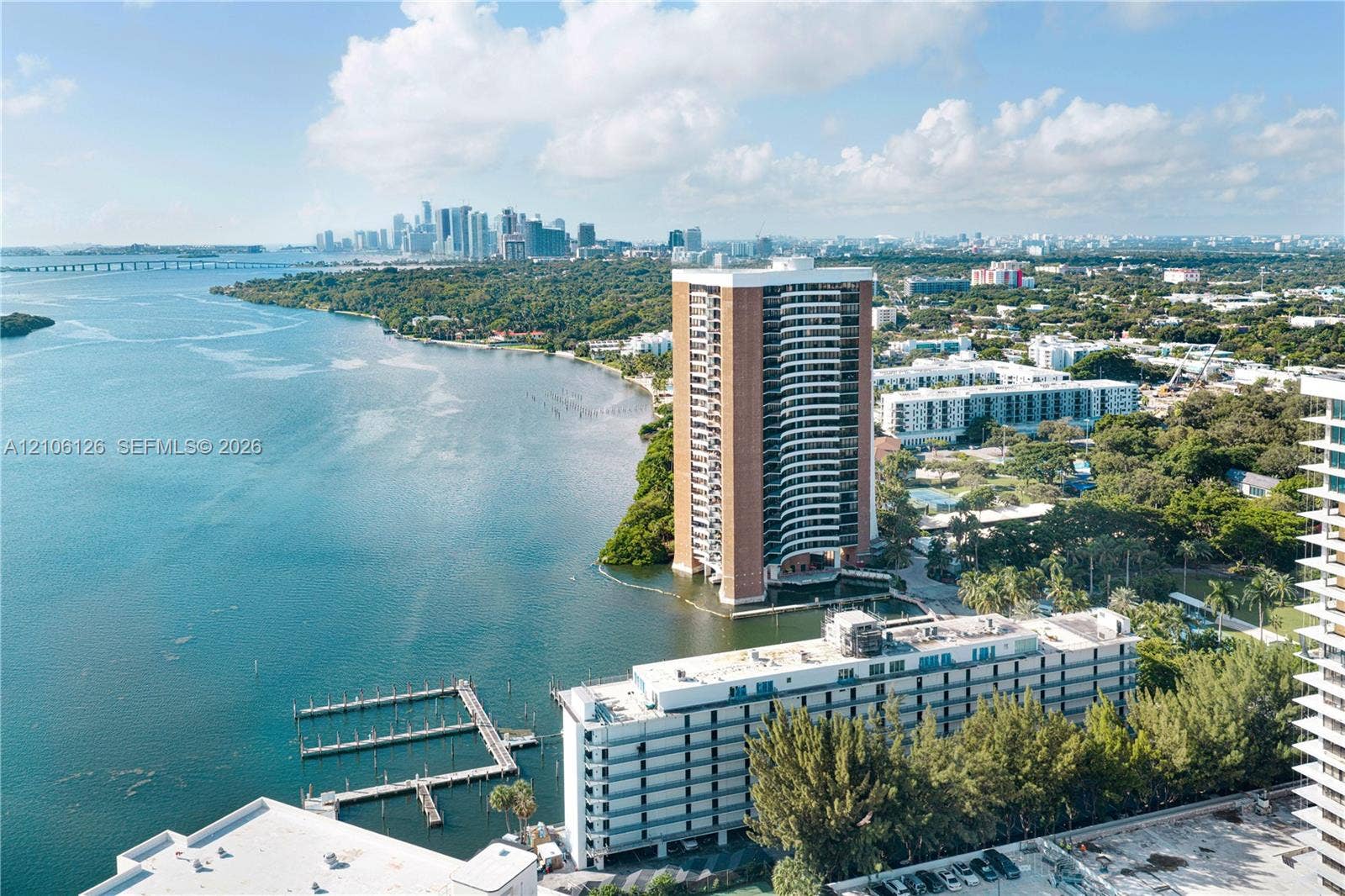 Aerial perspective featuring waterfront high-rise positioning, private dockage, coastal shoreline, and urban skyline backdrop