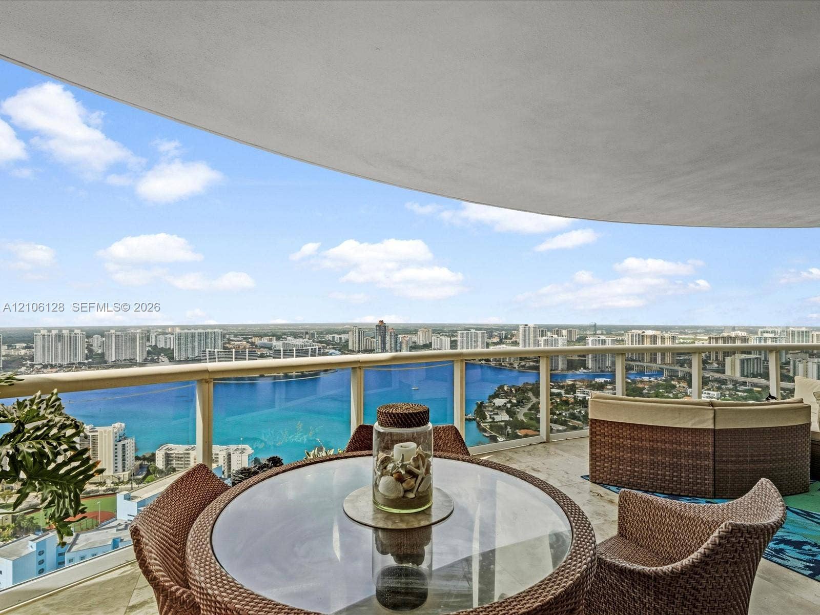Covered balcony featuring natural stone flooring and a glass-paneled metal railing