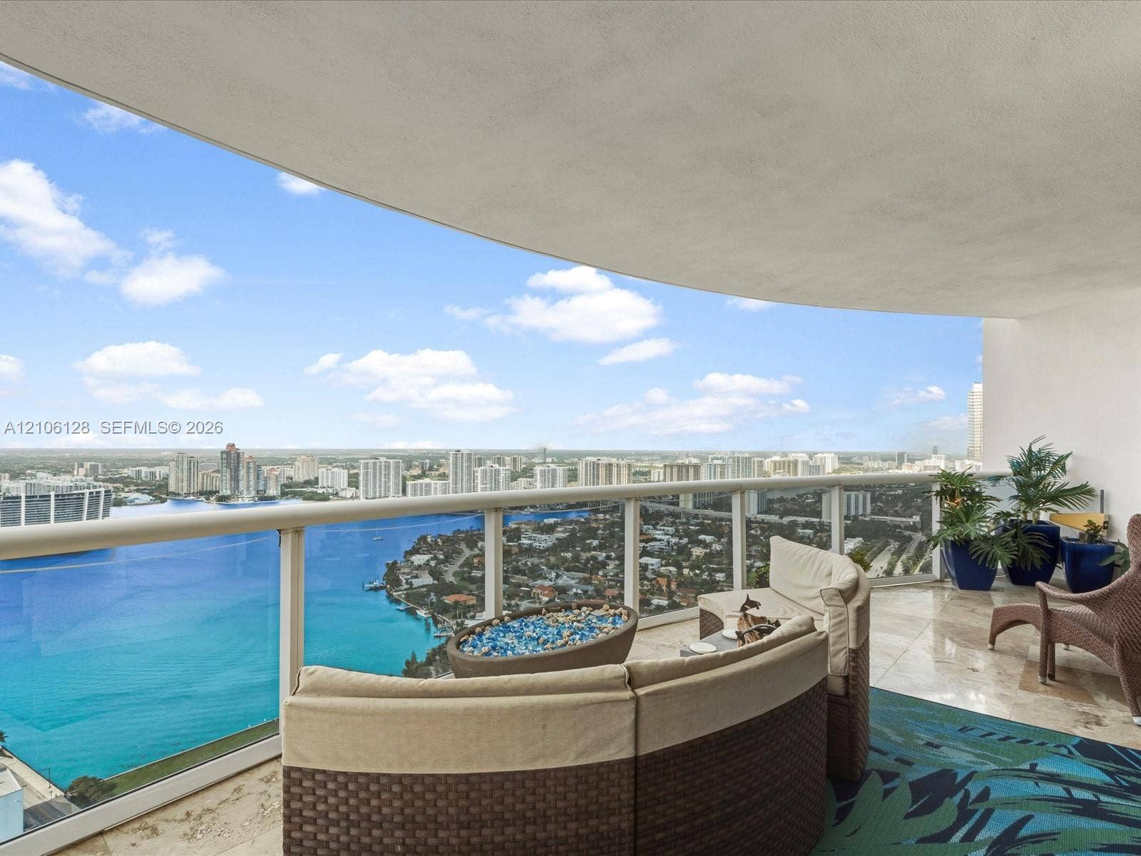 Covered terrace featuring polished stone flooring and glass panel railing