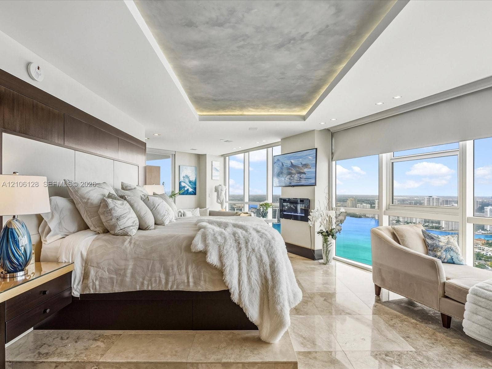 Floor-to-ceiling windows, stone tile flooring, built-in recessed ceiling lighting with textured inlay, and wall-mounted electric fireplace