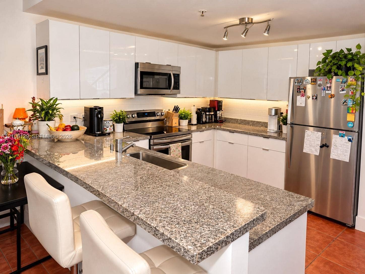 2740 SW 28th Terrace, #307, Miami, FL 33133 Kitchen featuring high-gloss white cabinetry, stone-finish countertops, stainless steel appliances, and integrated under-cabinet lighting