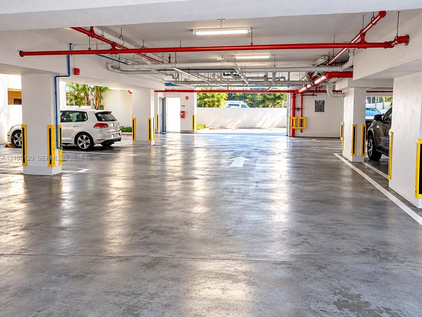 2740 SW 28th Terrace, #307, Miami, FL 33133 Covered parking garage featuring smooth concrete flooring, structural concrete support columns, and overhead fluorescent lighting