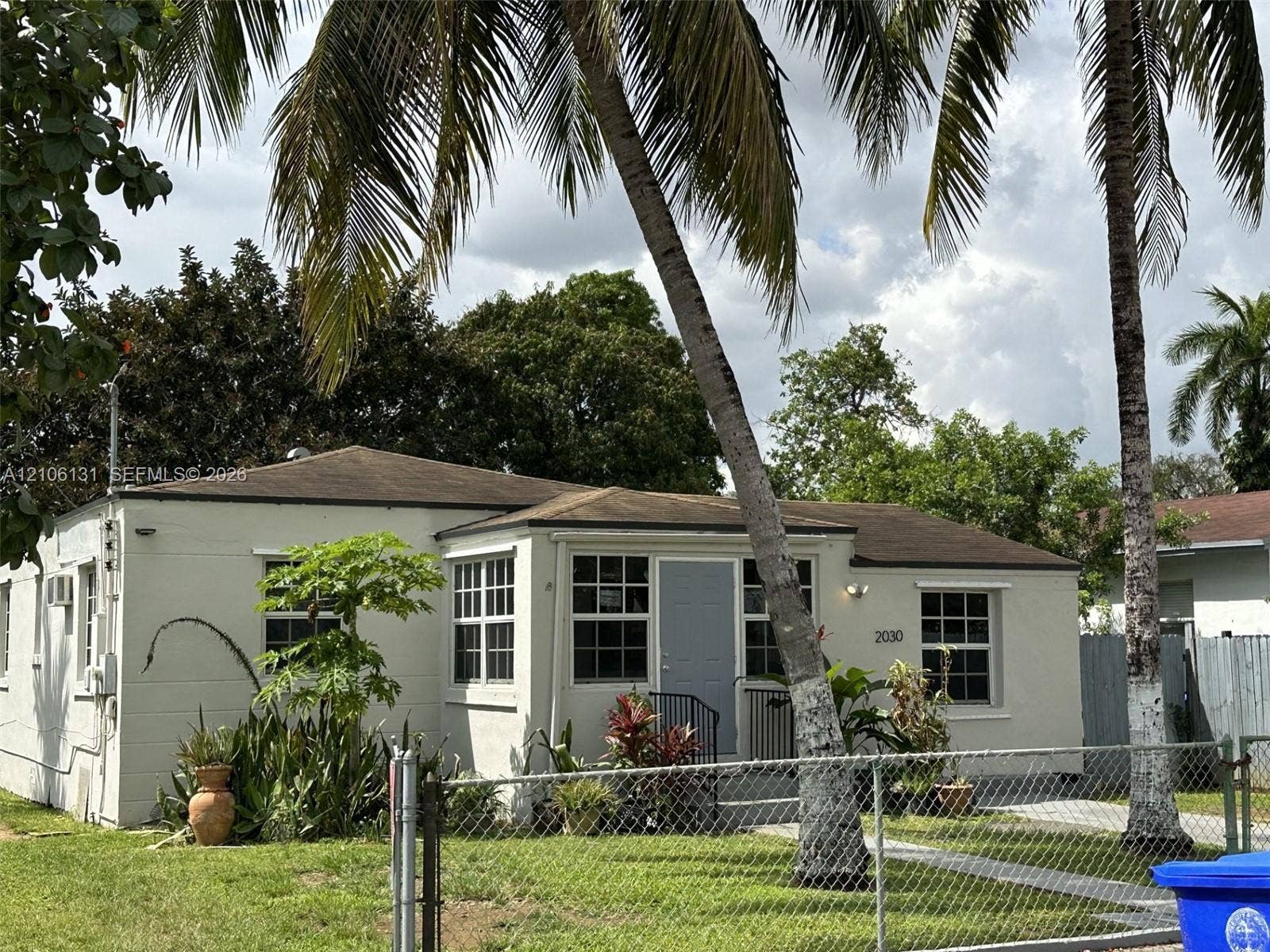 2030 NW 34th Street, Miami, FL 33142 Single-story exterior featuring light-toned masonry, multi-pane windows, a low-pitch roof, and mature palm trees