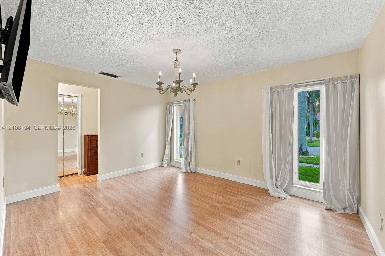Wood-finish flooring, multi-light chandelier, and large windows providing exterior exposure