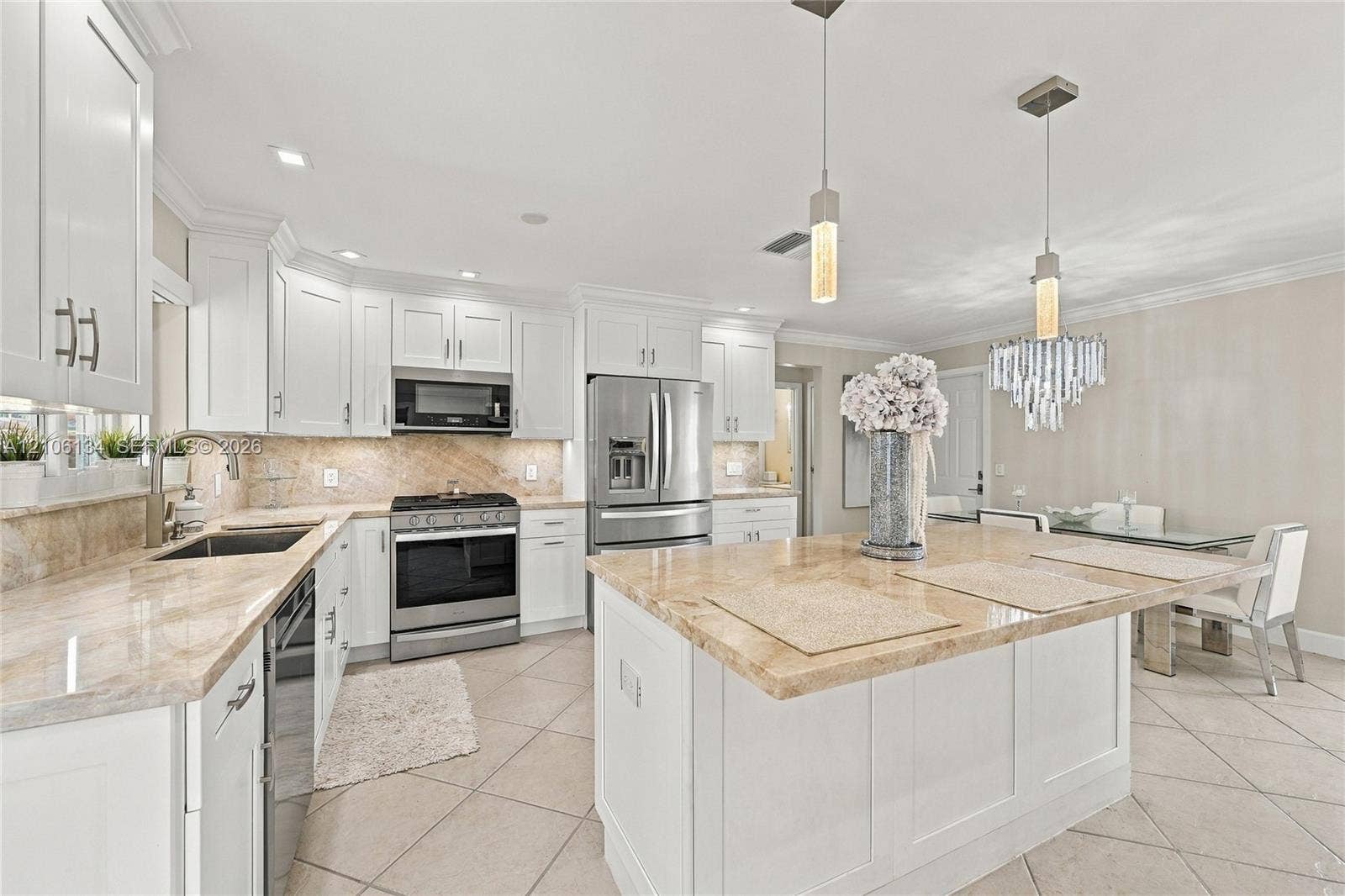 Kitchen featuring white shaker-style cabinetry, a large central island, stone-finish countertops, stainless steel appliances, and tile flooring