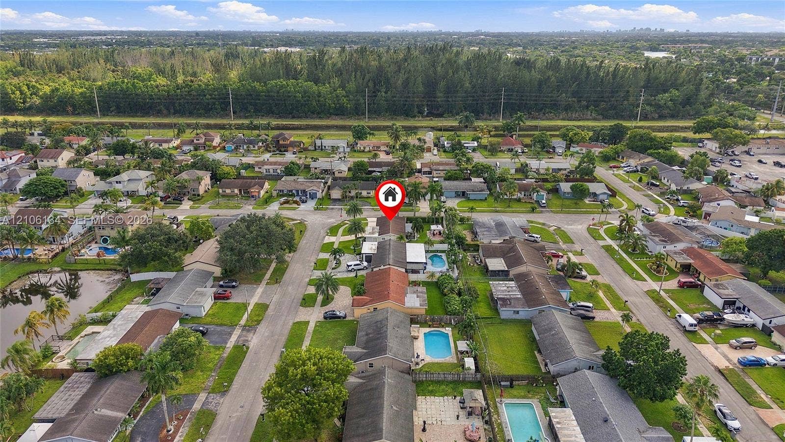 Aerial perspective of property featuring a tile roof, concrete driveway, and a fenced rear yard with a private swimming pool