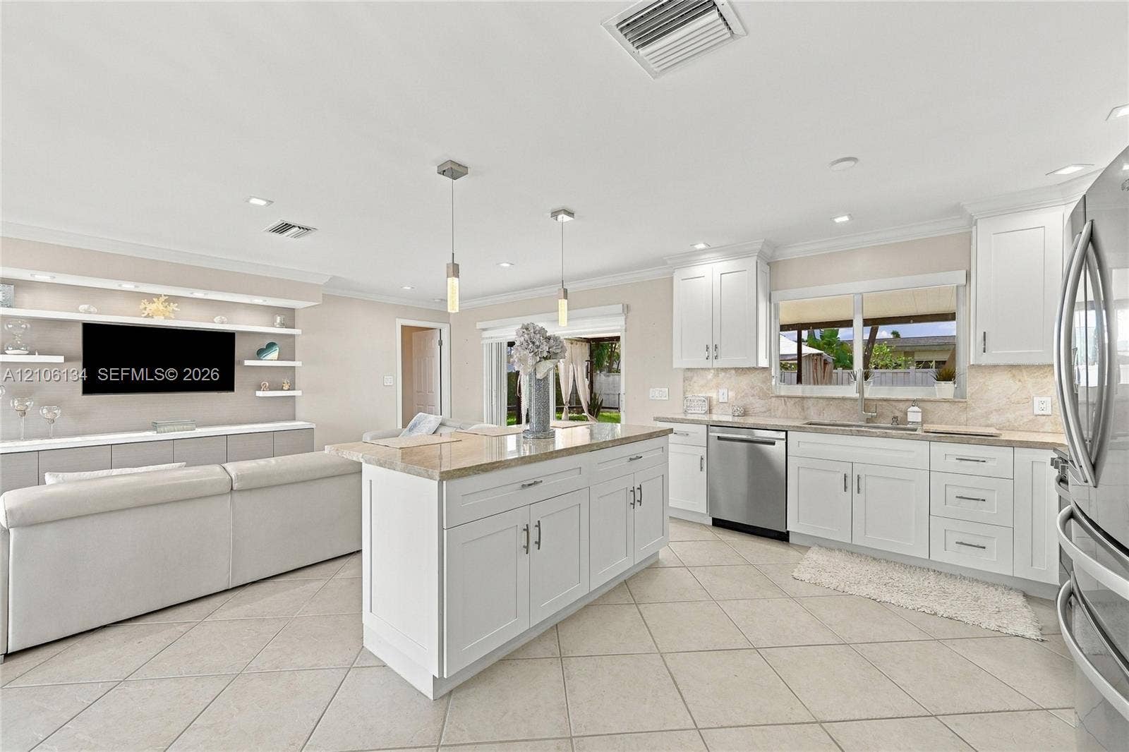 Kitchen featuring white cabinetry, center island with stone-finish countertop, stainless steel appliances, tile flooring, and integrated wall shelving