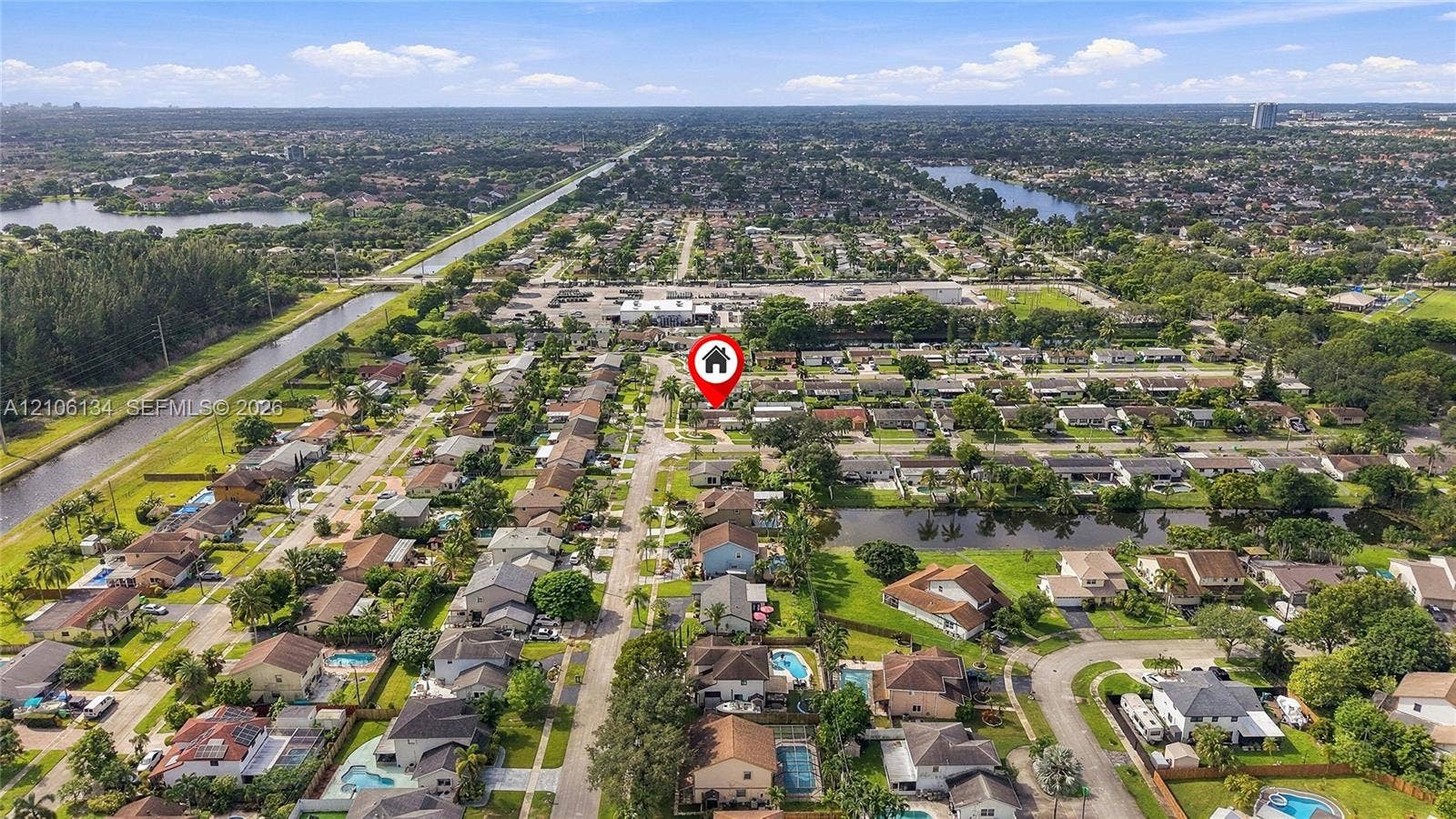 Aerial perspective of a suburban neighborhood featuring a grid street pattern, mature canopy trees, residential parcels, and proximity to regional waterways