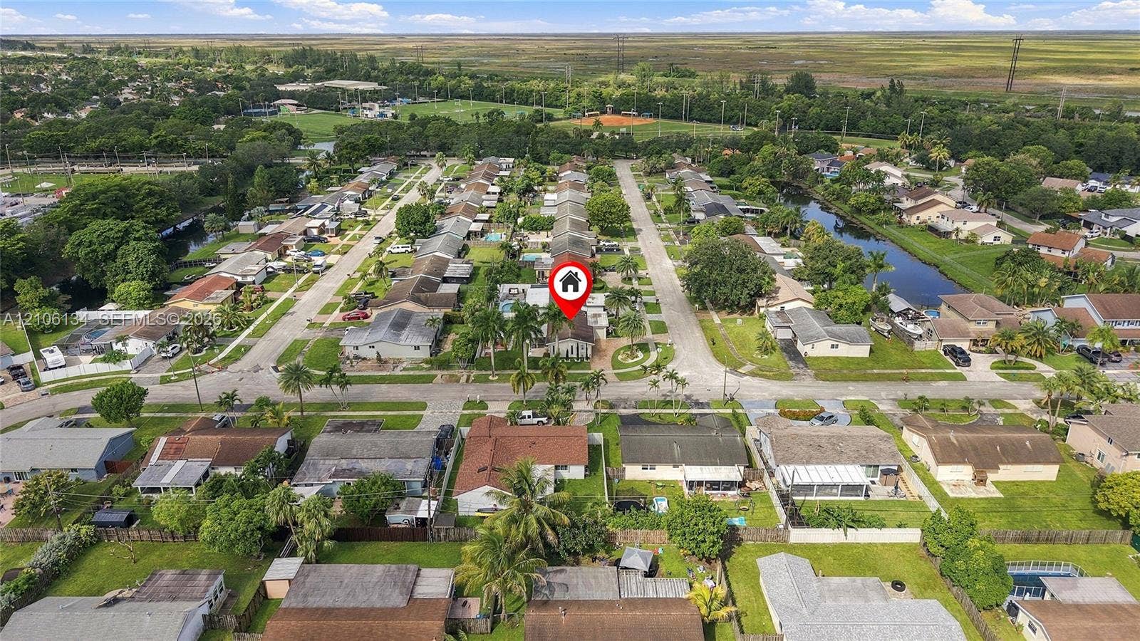 Aerial perspective of a single-story residence situated on a landscaped lot with mature palms